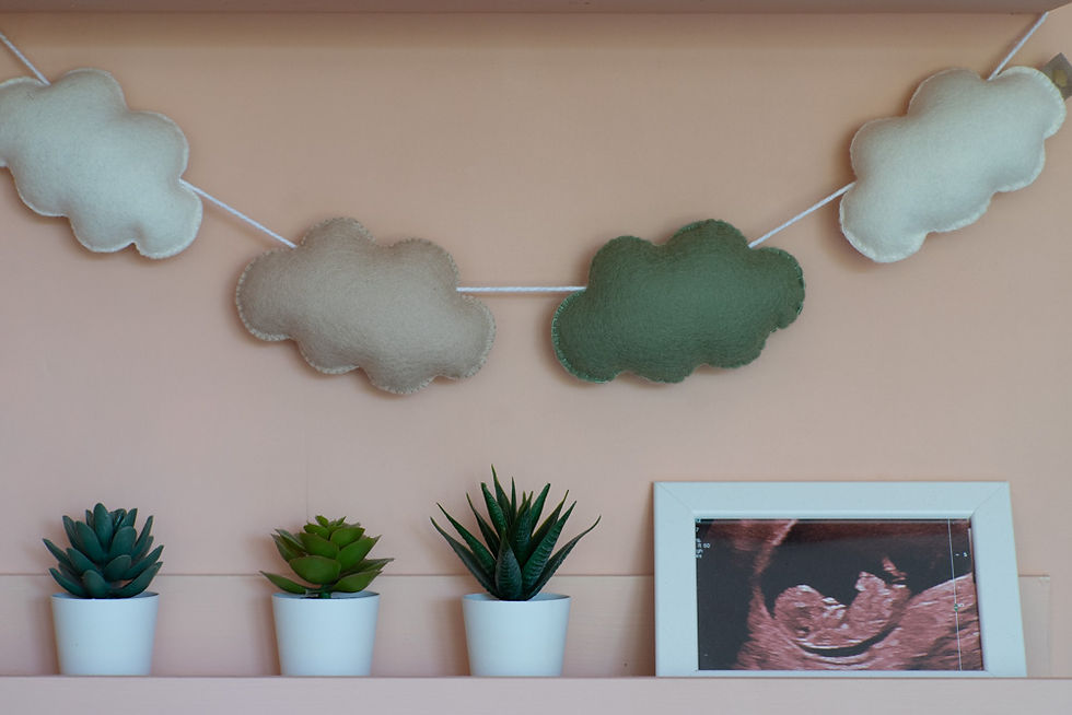 Handgemaakte viltslinger met wolkjes in neutrale kleuren – duurzame babykamerdecoratie van natuurlijke materialen.