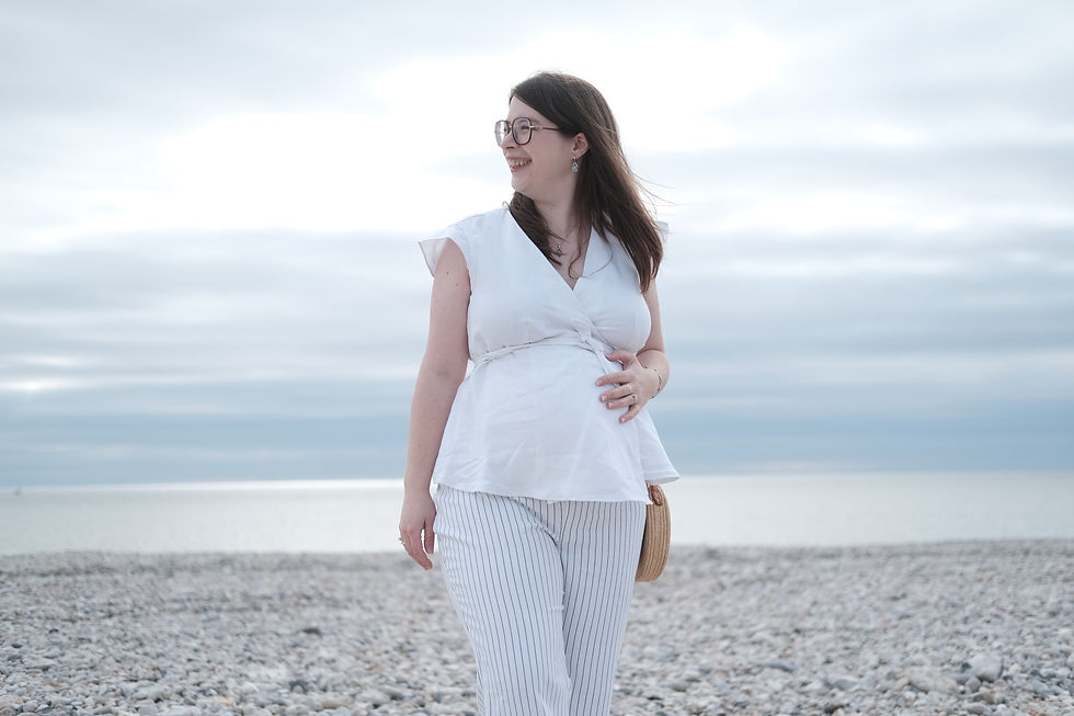 femme enceinte de face avec une blouse cache coeur blanche et un pantalon de grossesse