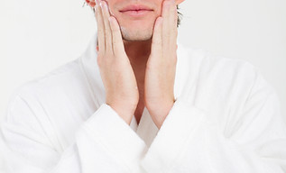 Man with happy smile applying moisturizi