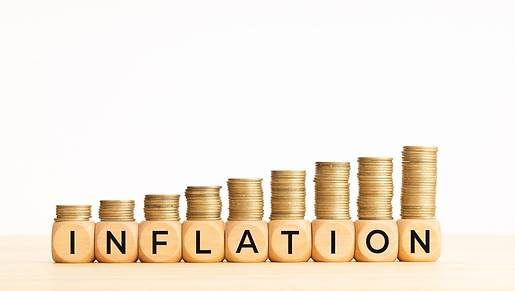 There are nine stacks of coins, each one taller than the last one, forming an exponential curve. Wooden blocks spell out the word "inflation".