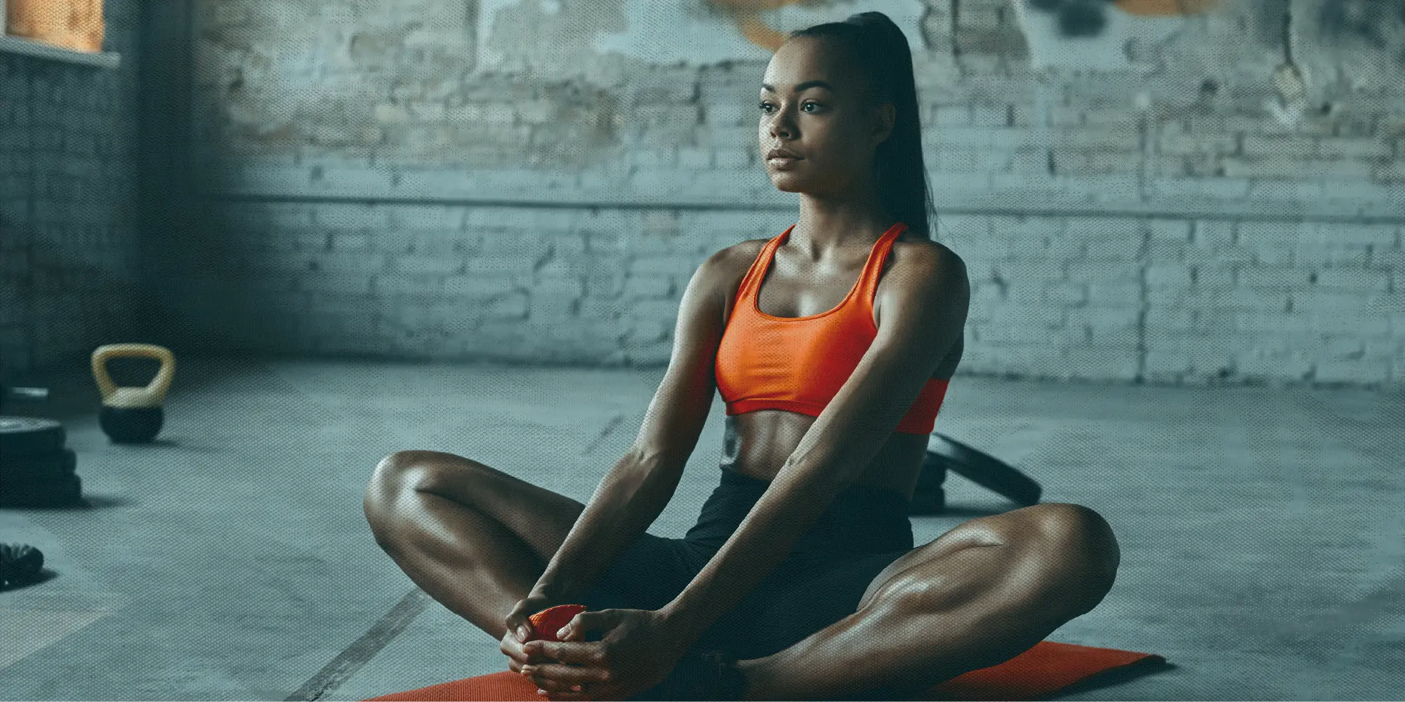 What To Do This Weekend | Health SZN | A beautiful brown woman stretching on the floor while doing progressive muscle relaxation wearing an orange sports bra with definedabs