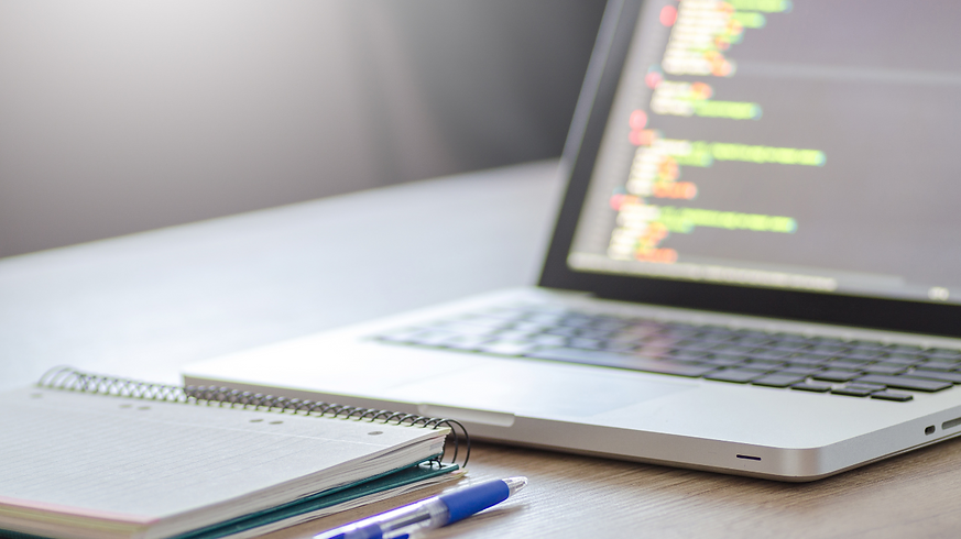 Laptop with computer coding and a notebook and mechanical pencil in front