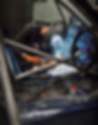 Person welding a roll cage inside a car