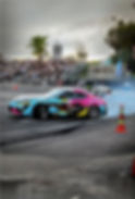 Brightly colored drift car smoking tires on track
