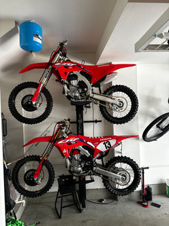 Two dirt bikes stored on a wall mounted storage lift. 