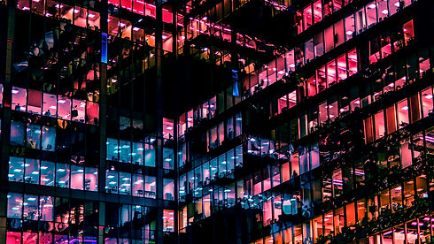 Modern building at night, windows glowing in neon colors