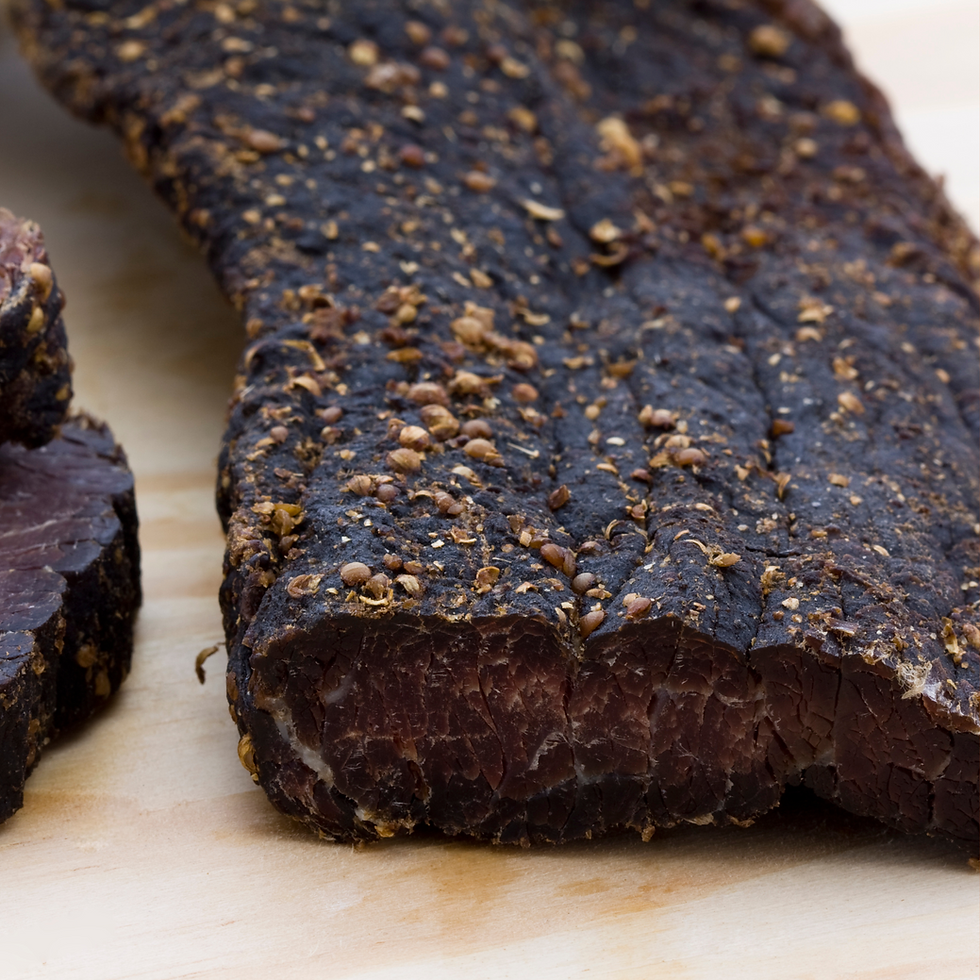 Close-up of dark, seasoned biltong slices on a wooden surface, showcasing rich textures and earthy tones.