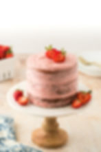 Close-up view of a semi naked frosted cake decorated with fresh flowers