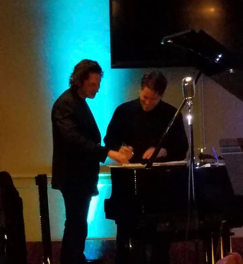 Richie collaborating with someone around a piano