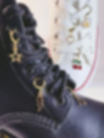 A black boot decorated with a gold star and black lightning bolt shoelace charm, demonstrating how to style footwear.