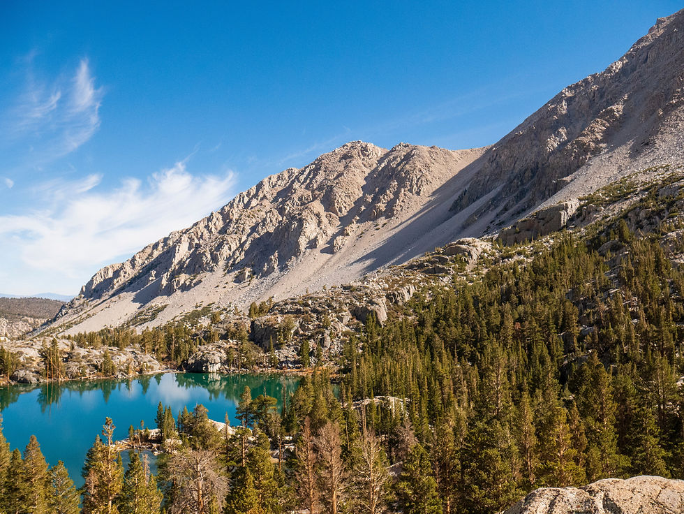 small lake surrounded by trees and grey peak