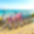 Six colorful bicycles on sandy beach, vibrant pink, blue, and white frames, ocean and sky in background, sunny and cheerful mood.