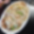 Plate of fried rice with vegetables and meat on a dark table. A person’s hand is visible. The mood is casual.
