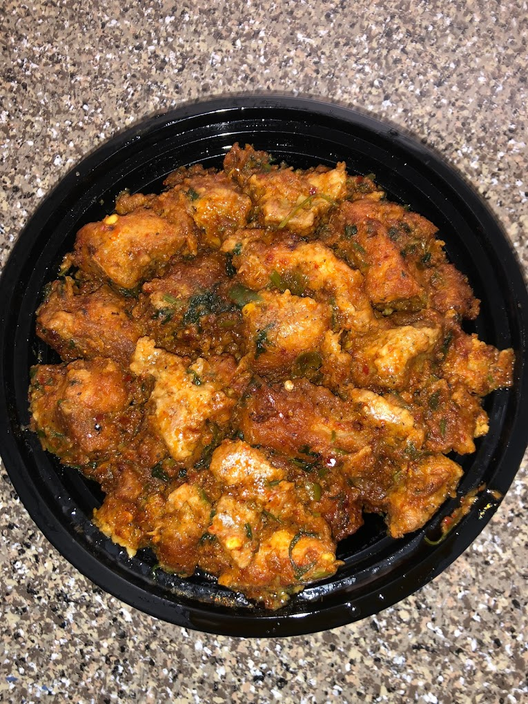 Spicy, golden-brown chicken curry on a black plate, set against a speckled countertop. Rich textures and vibrant colors.