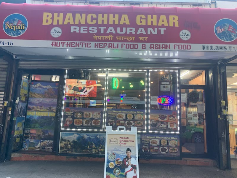 Front of Bhanchha Ghar Restaurant with a red sign. Displays images of Nepali food, “OPEN” neon sign, and advertisement board outside.