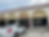 Storefront of "Flavors Indian Kitchen" with people entering. A white car is parked outside. Overcast sky and "OPEN" sign visible.