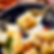 Close-up of cheese cubes with red chili flakes on a decorative spoon above a blue patterned plate. Bright, colorful, and appetizing scene.