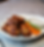 Chicken wings with a crispy texture on a plate, served with carrot and celery sticks, and two white dipping sauces on a gray table.