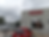 Benihana restaurant exterior with gray sky. Red and white cars parked in front. Red "BENIHANA" sign on building. Trees in the background.