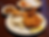 Plate with fried chicken, mashed potatoes with gravy, a biscuit, lemon wedges. Side of beans, basket of rolls in background. Cozy setting.