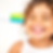 Child smiling brightly, holding a colorful toothbrush with water dripping off the bristles. Background is white, creating a cheerful mood.