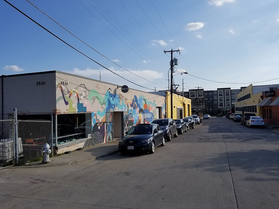 Street view of a building with colorful mural and text CERVEJERIA57. Cars line the street; clear sky and urban background. Calm setting.