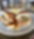 Poppy seed bun sandwich with slaw and chicken on a gray plate, served with fries. Wooden table setting, warm ambiance.