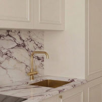 Projekt luksusowej strefy zmywania: marmurowy zlewozmywak i złota bateria na tle kamienia.