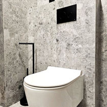 Podwieszana toaleta w nowoczesnej łazience wykończonej szarym, marmurowym kamieniem, czarny przycisk spłukujący i akcesoria.