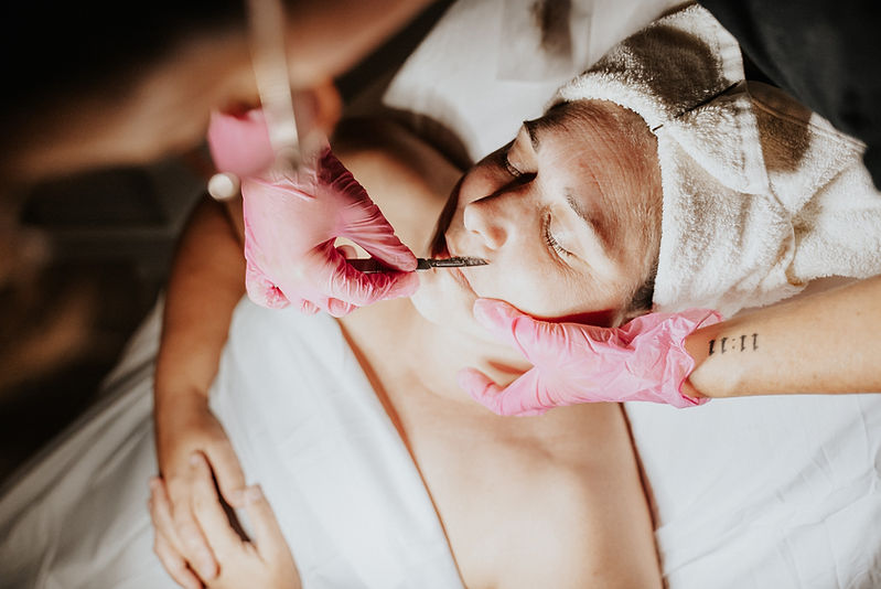Woman receiving microneedling treatment with pink gloves and medical tools SERVICES microneedling near me