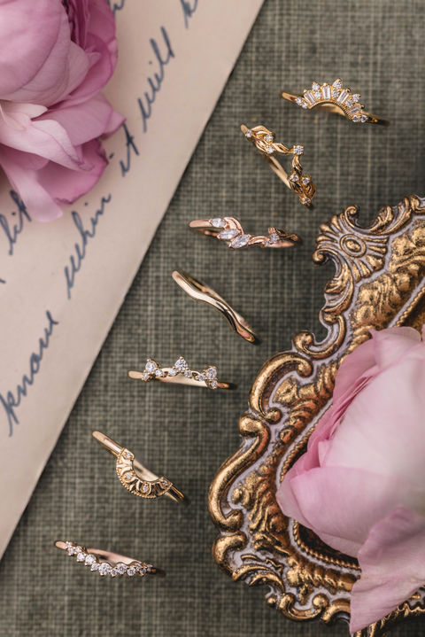 Gold rings and floral accents on a decorative tray with handwritten script.