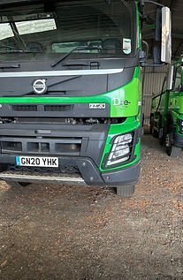Two green Volvo trucks parked in garage