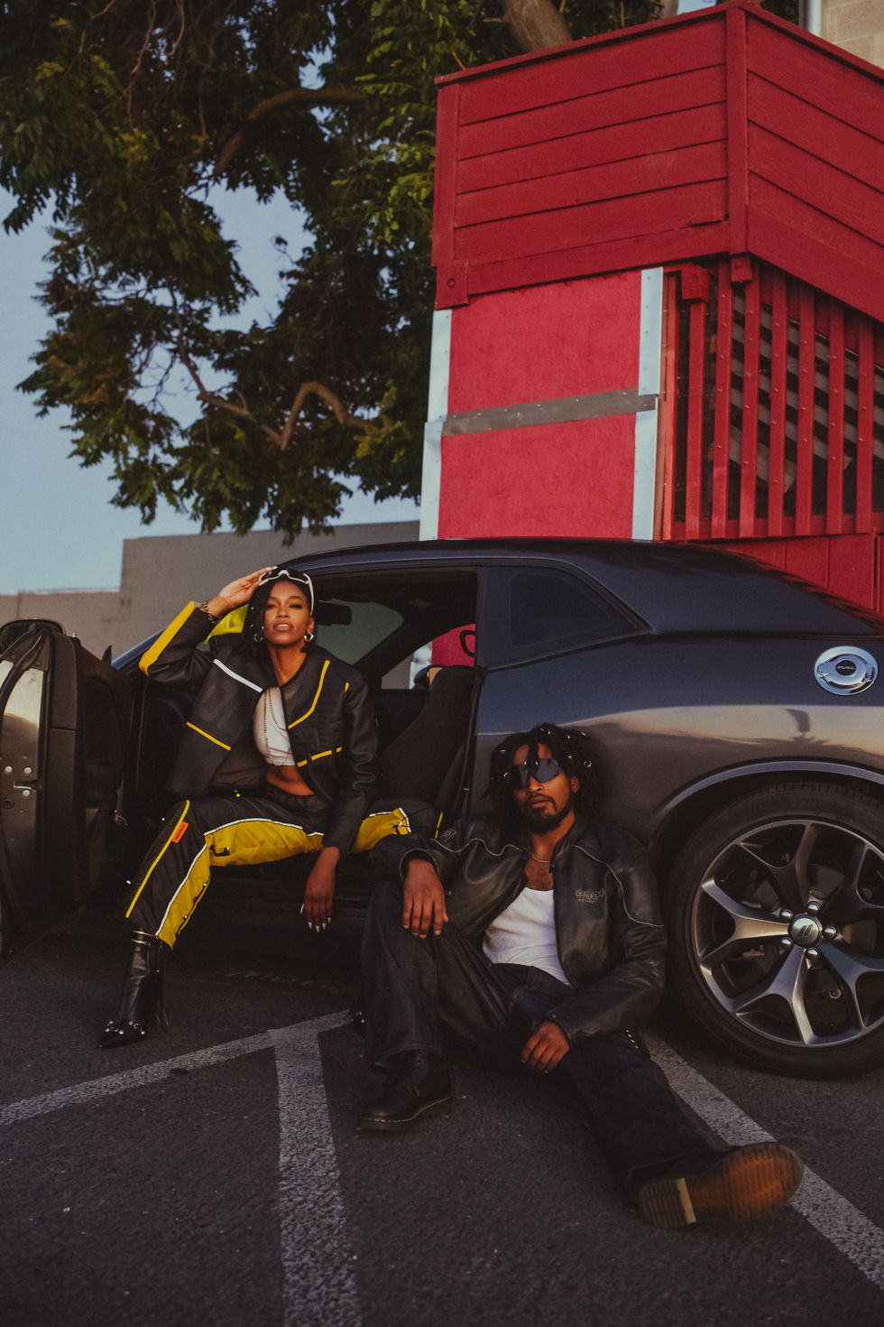 Black couple posing in front of black car