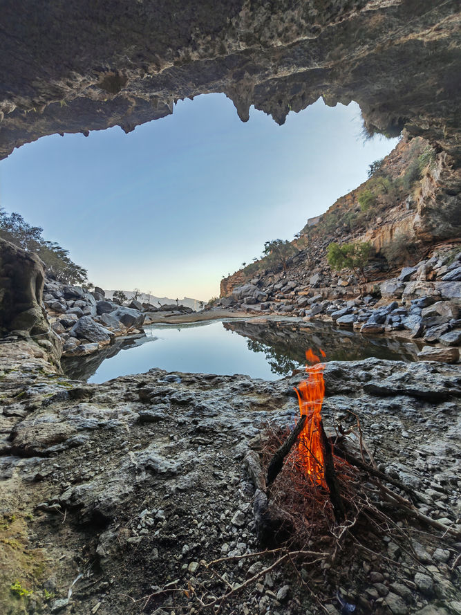 Traveler standing inside a cave opening during the Jabal Shams lake abseiling adventure
