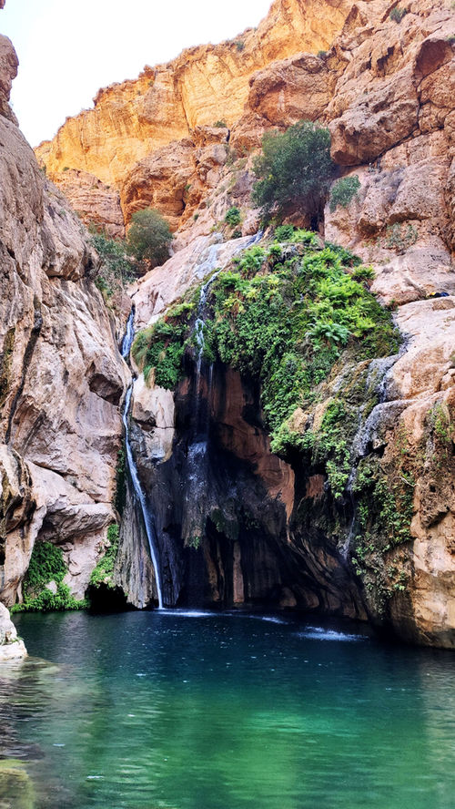 Jahal Waterfall flowing into a turquoise natural pool during a one-day hiking adventure in Oman