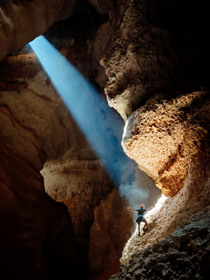 Sunbeam illuminating rock formations inside the 7th Hole cave during a guided caving tour in Oman