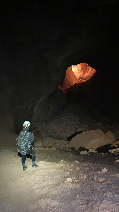 Explorer inside a vast underground chamber during the Funnel Cave to Tahry Cave caving tour in Oman
