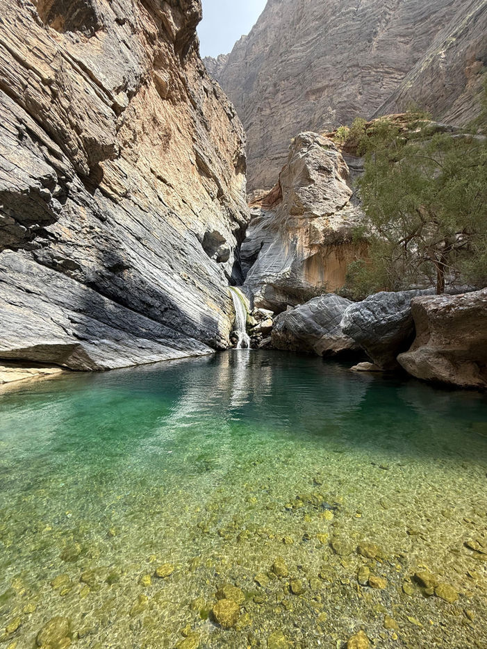 Hikers exploring Wadi Sa’ada Oman with narrow gorges, natural pools, and scenic mountain trails.