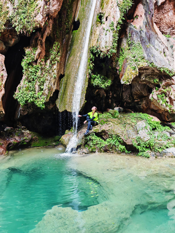 Turquoise natural pool and small waterfall in Wadi Al Hajir during a one-day canyoning tour in Oman