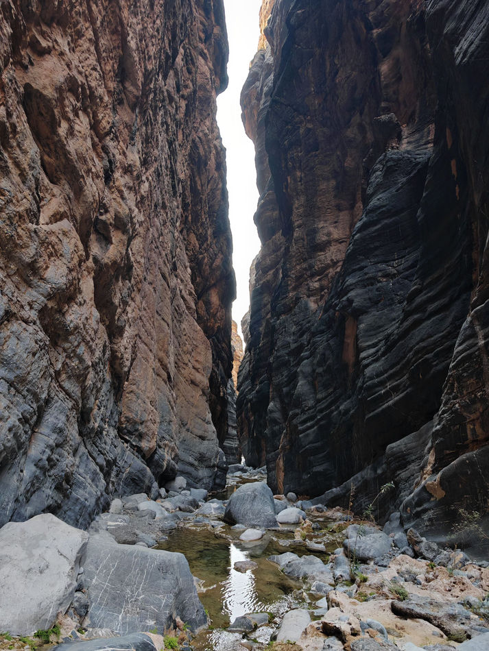 Narrow canyon passage with boulders in Wadi Al Hajir during a guided canyoning adventure