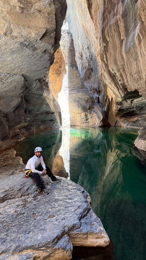Adventurer standing beside an emerald pool in Wadi Nakhr during a guided canyoning trip