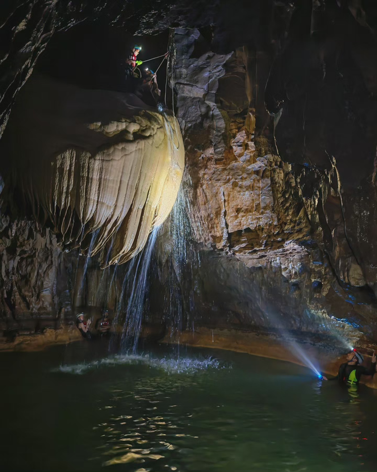Adventurers inside Al Hoota Cave Oman exploring underground passages and rock formations on a 1-day caving adventure.