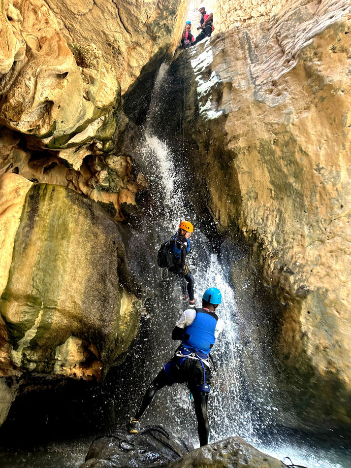 Canyoner descending beside a waterfall during the Wadi Ta’ab canyoning adventure in Oman