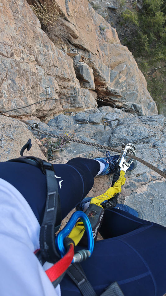 Adventurer preparing on a cliff section during the 150m abseiling experience in Jabal Shams