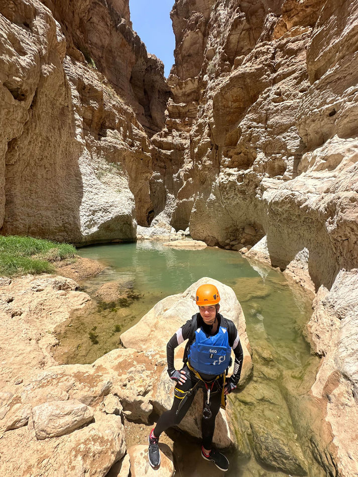 Traveler standing beside a green canyon pool during the Wadi Ta’ab canyoning tour in Oman