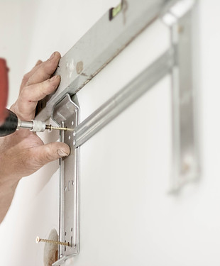 Handyman installing a TV mounting bracket in a home in Leland, NC.