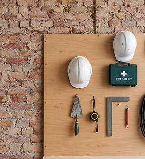 White hard hats, first aid kit and tools hanging on a construction panel