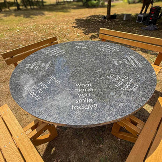 solid oak picnic table and freestand bench located in a garden with granite top with wording