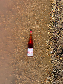 Botella de Laguna Rosa parcialmente sumergida en las aguas de la Laguna Rosa de Torrevieja
