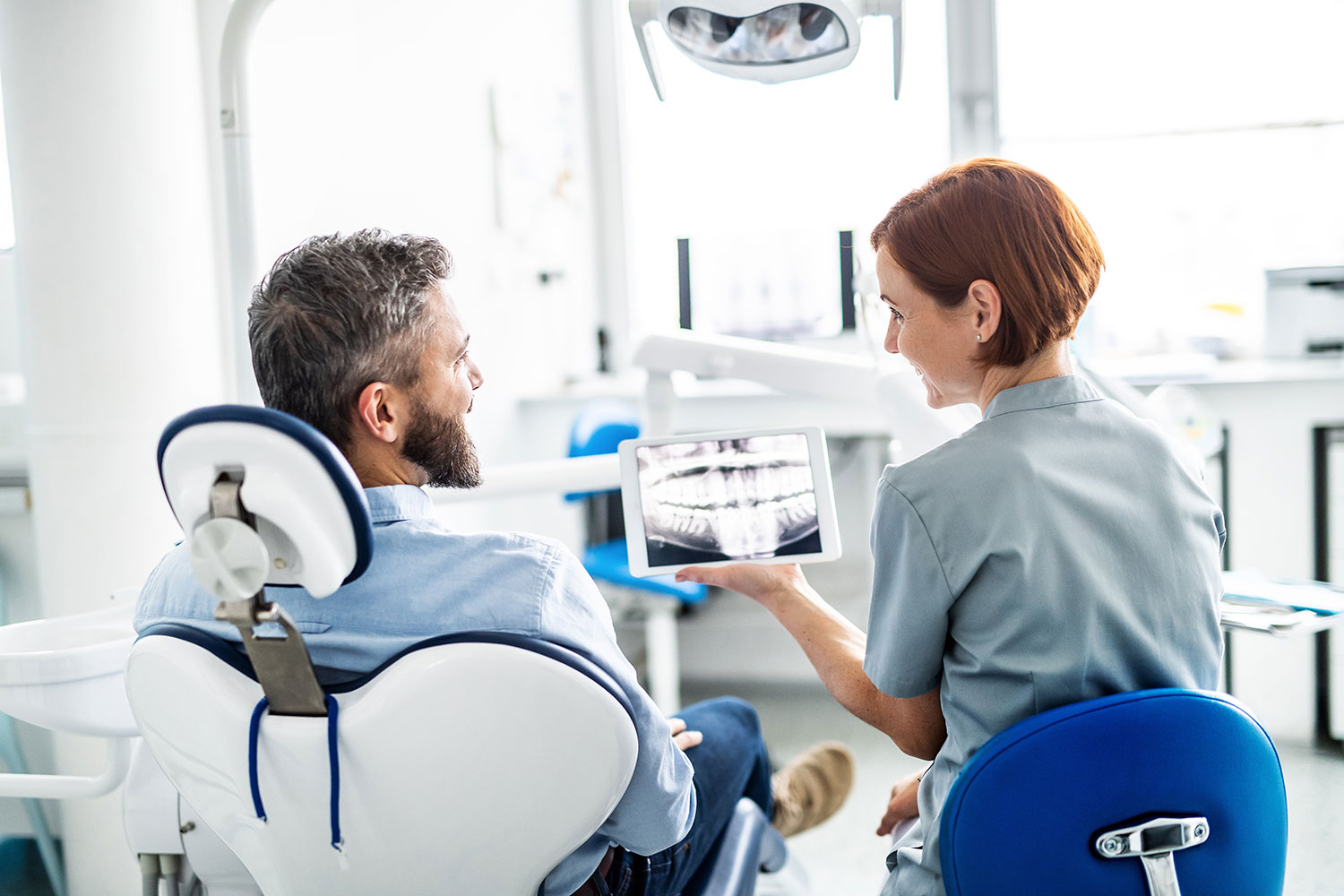 Dentist showing a dental X-ray on a tablet to a patient